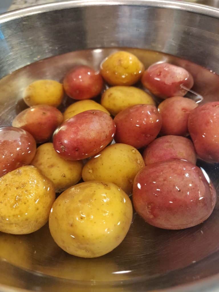 Red and yellow potatoes soaking in bowl of water