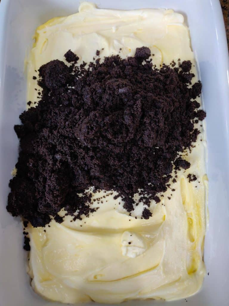 Pile of crushed oreos on filling for dirt cake