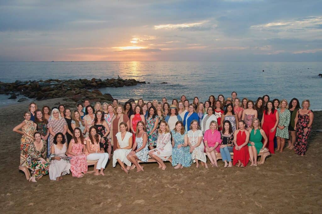 67 Team Members standing on the beach at sunset