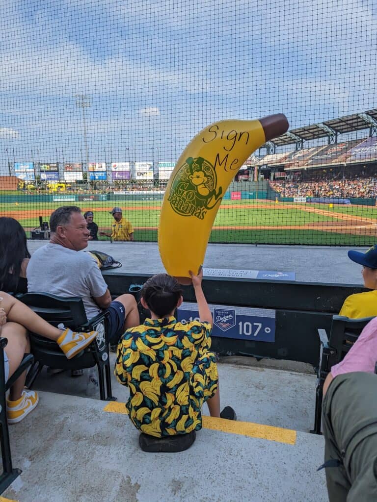 Kid dressed in banana gear holding a huge banana