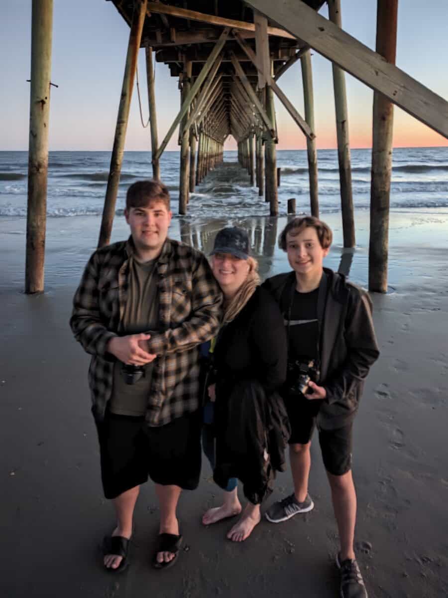 Tyler, Shelly and Cole standing under the Holden Beach Pier during sunset