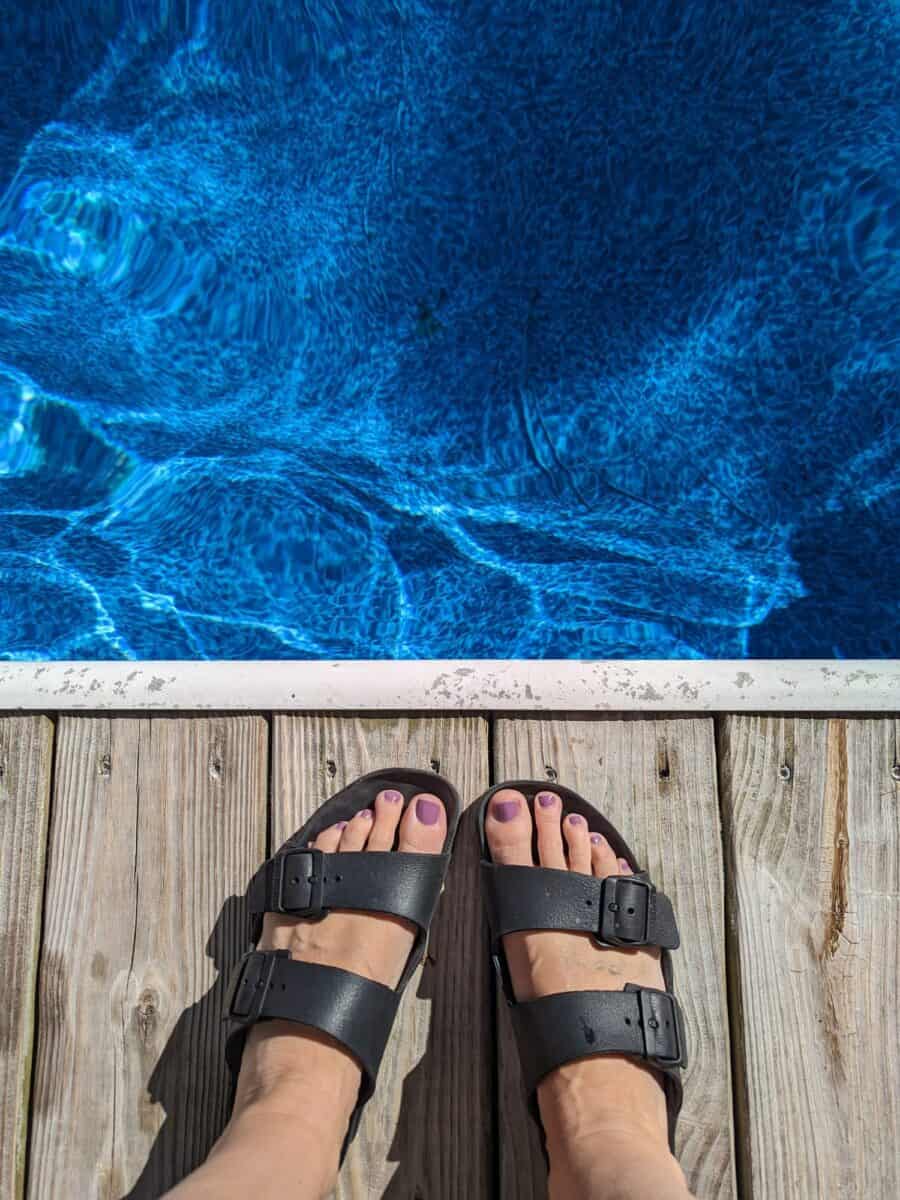 View of my feet standing next to the edge of pool