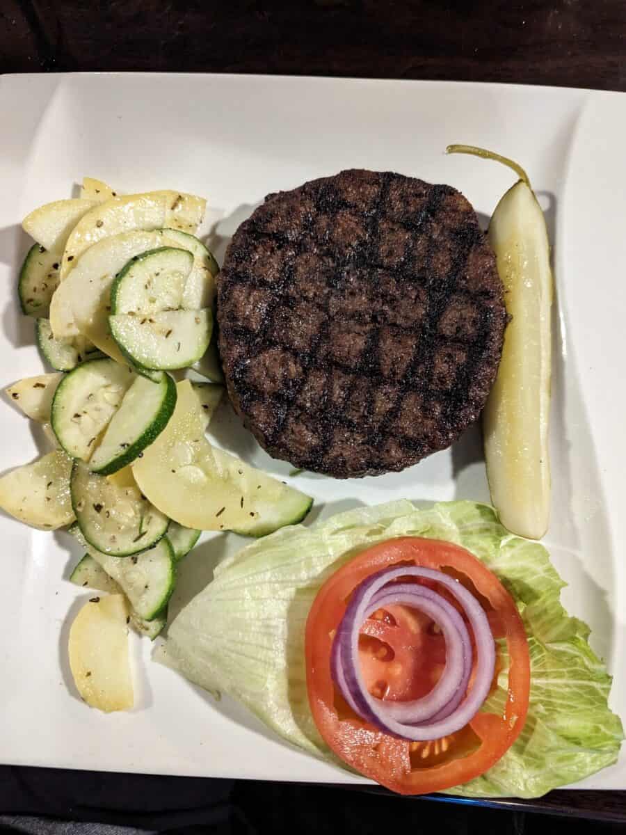 Bunless burger with lettucem tomato, red onion, pickle and veggies on a plate