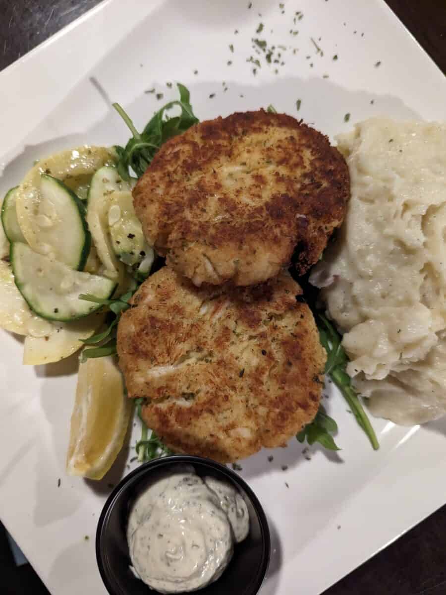 Crab cakes with mashed potatoes, veggies and mashed potatoes on plate