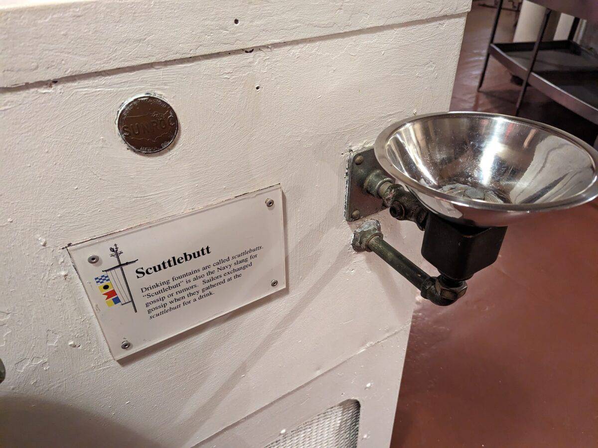 Sign of scuttlebutt and a drinking fountain on naval ship