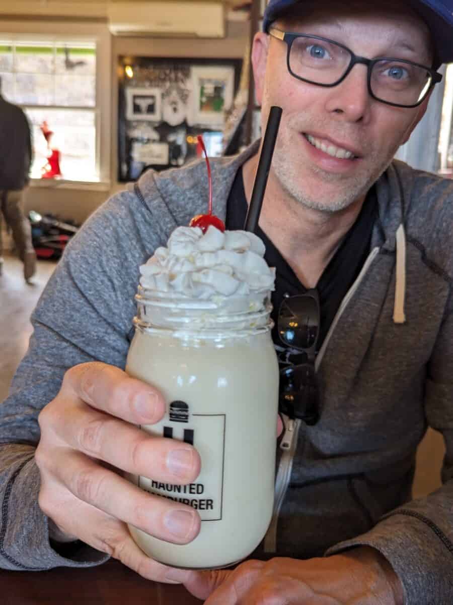 John holding his vanilla milkshake topped with whip cream and a cherry